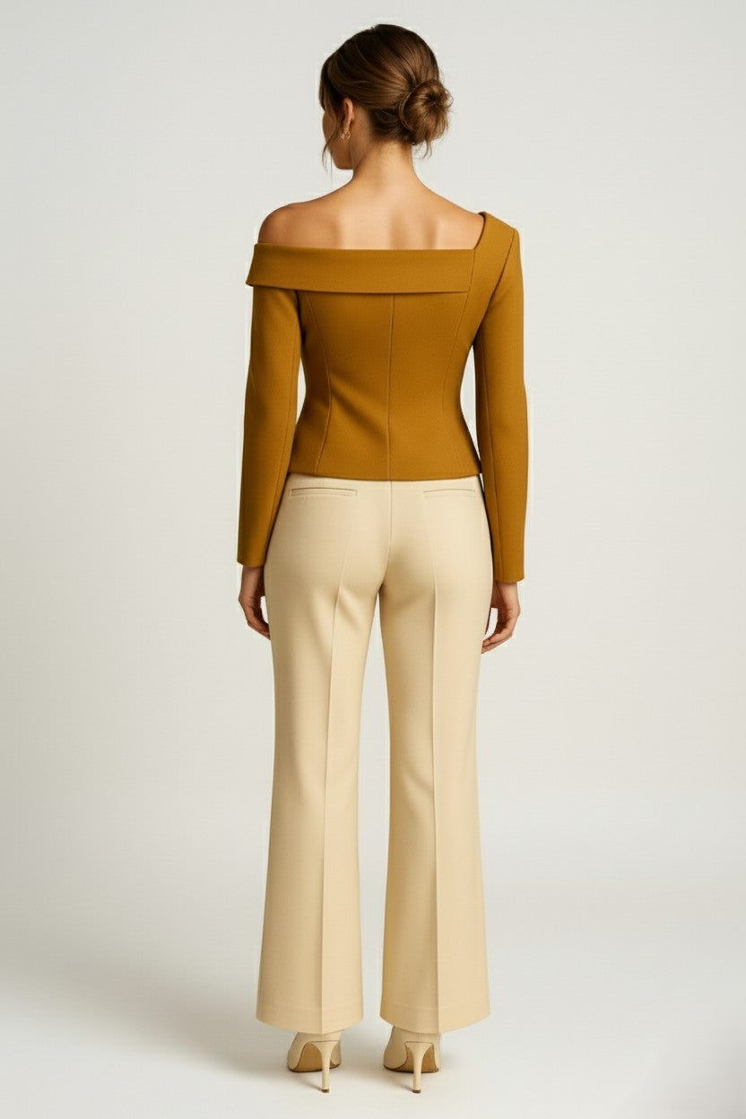 Woman wearing a asymmetrical cashmere top and beige pants on a white background