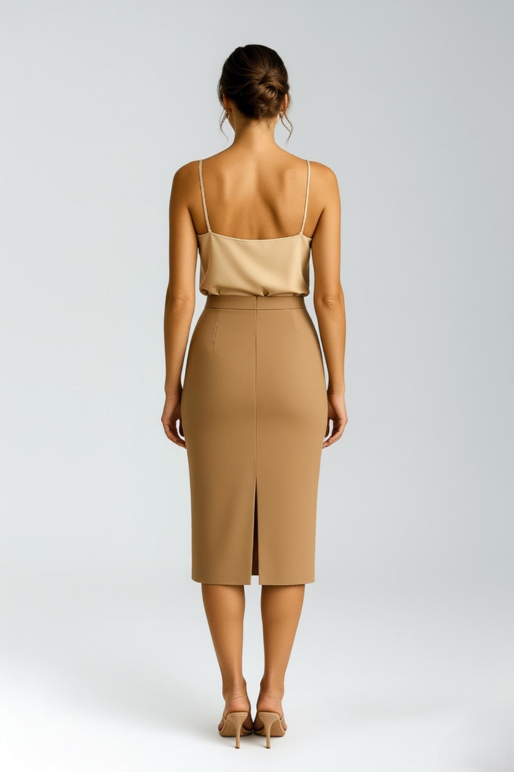 Woman wearing a beige silk camisole top and cashmere pencil skirt on a white background