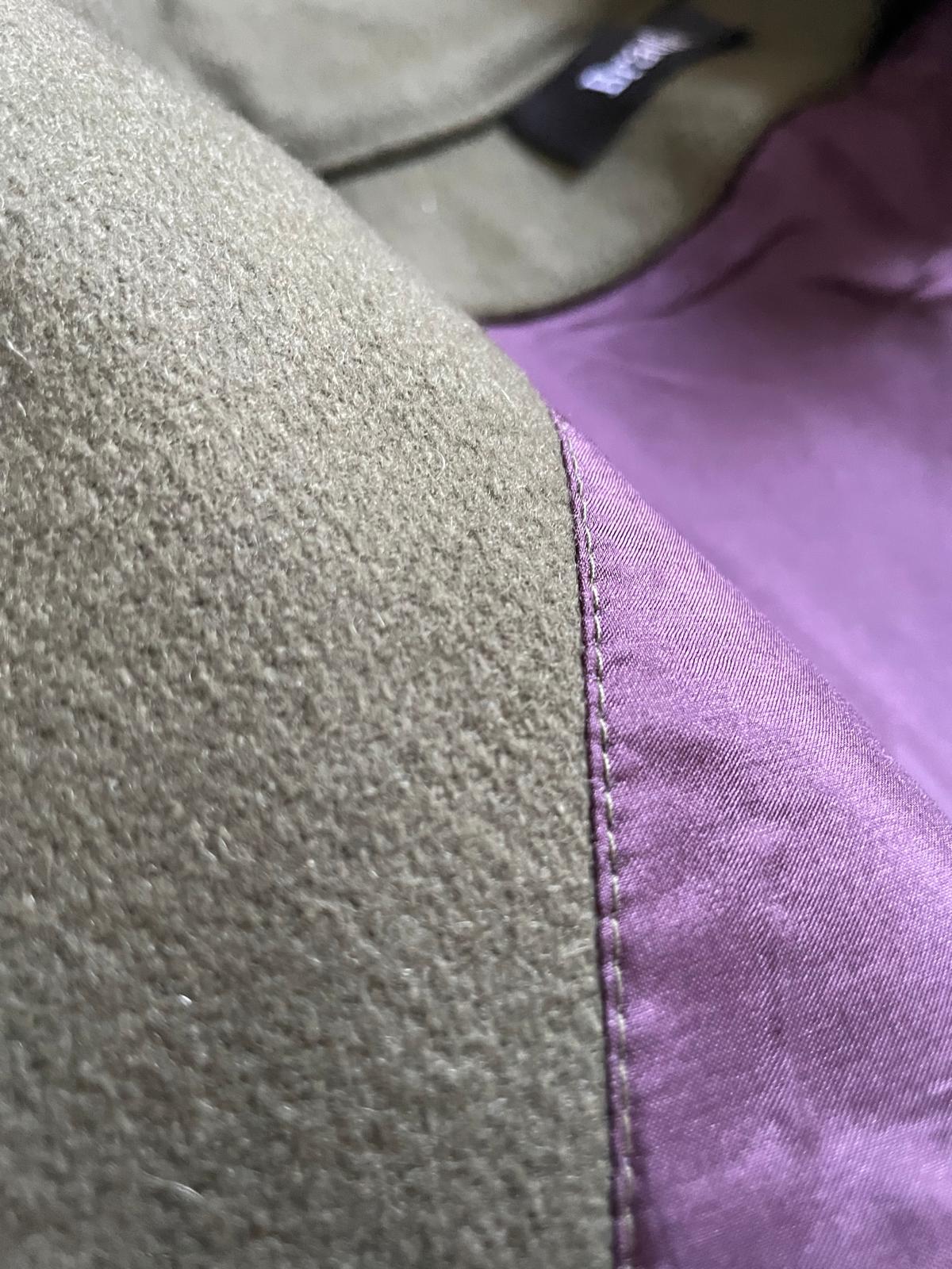 Close up seam of olive wool vest and burgundy silk lining.