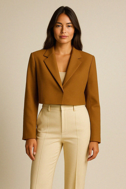 Woman wearing a cropped cashmere jacket and beige pants against a neutral background