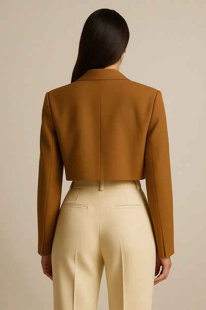 Woman wearing a cropped cashmere jacket and beige pants against a neutral background