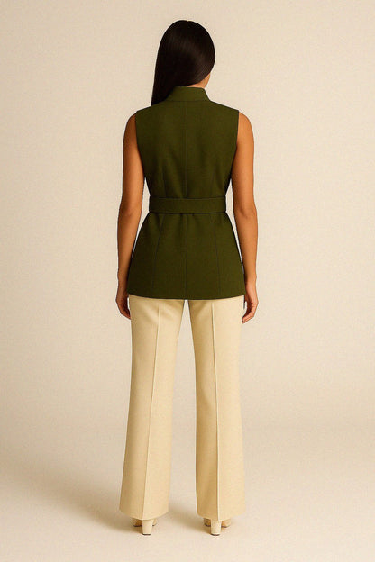 Woman wearing a olive wool vest and beige pants on a beige background