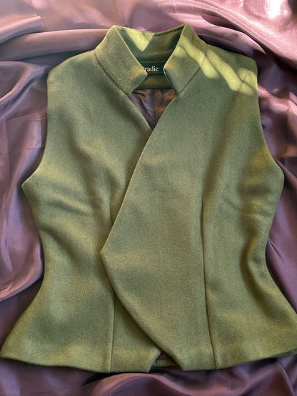 Olive wool vest laying flat on burgundy silk fabric.