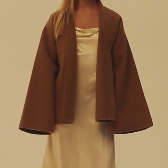 Woman wearing a 25 momme champagne silk slip dress under the double faced cashmere wrap coat.