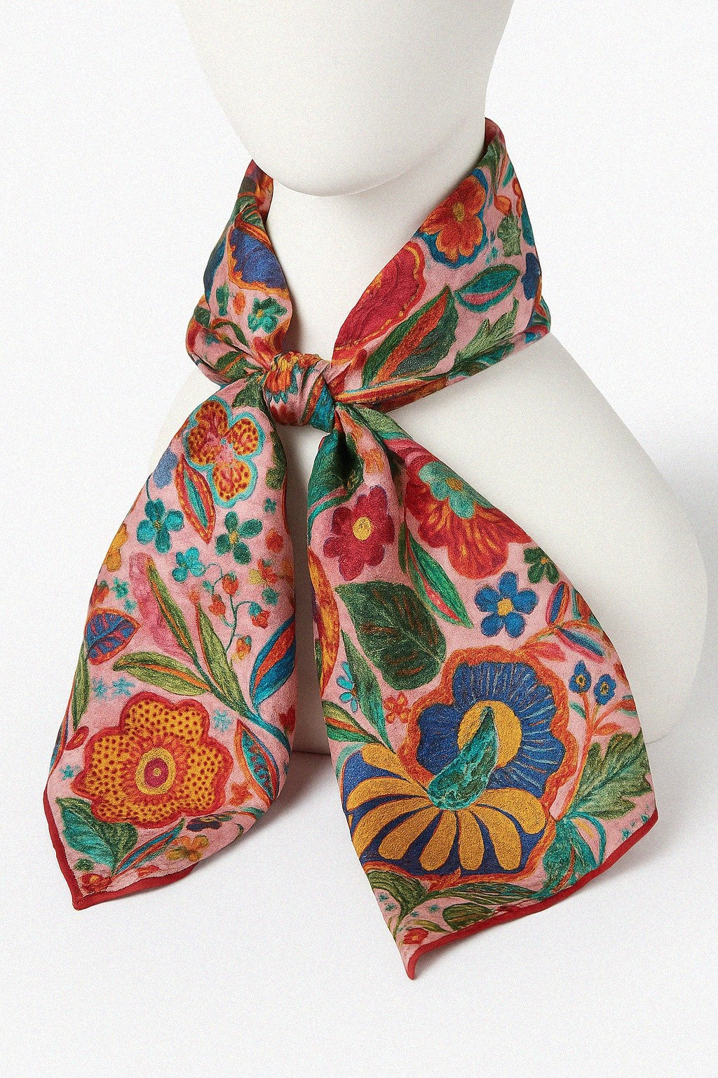 Colorful floral scarf made from cashmere and silk tied around a mannequin head on a white background