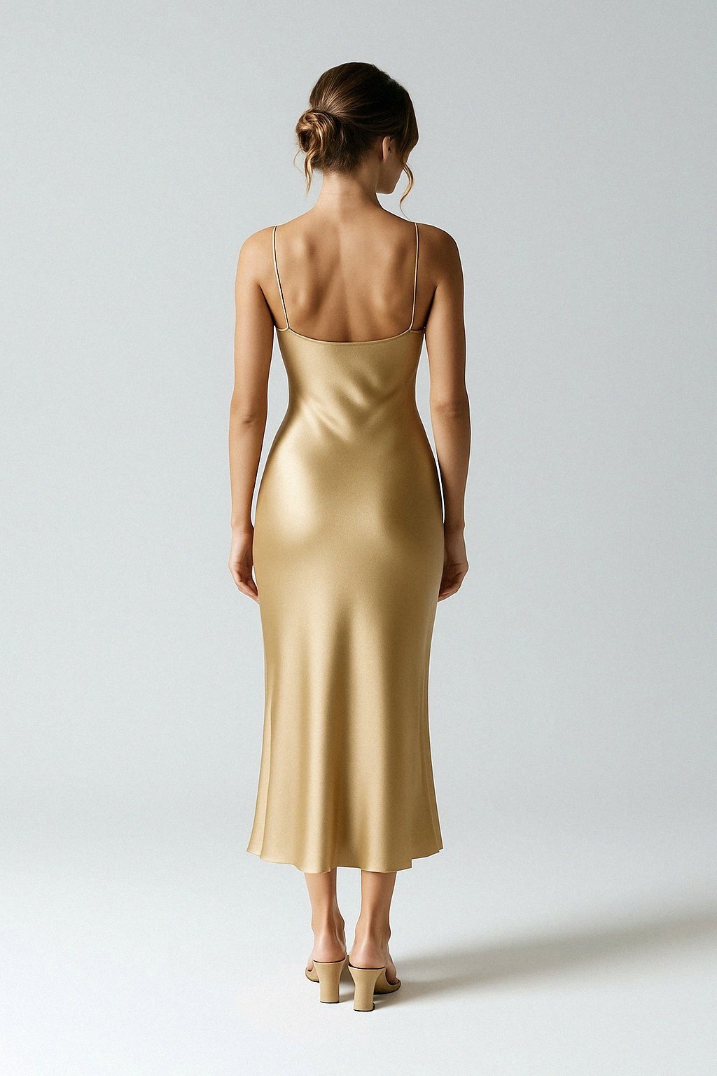 Woman wearing a silk slip dress against a plain background