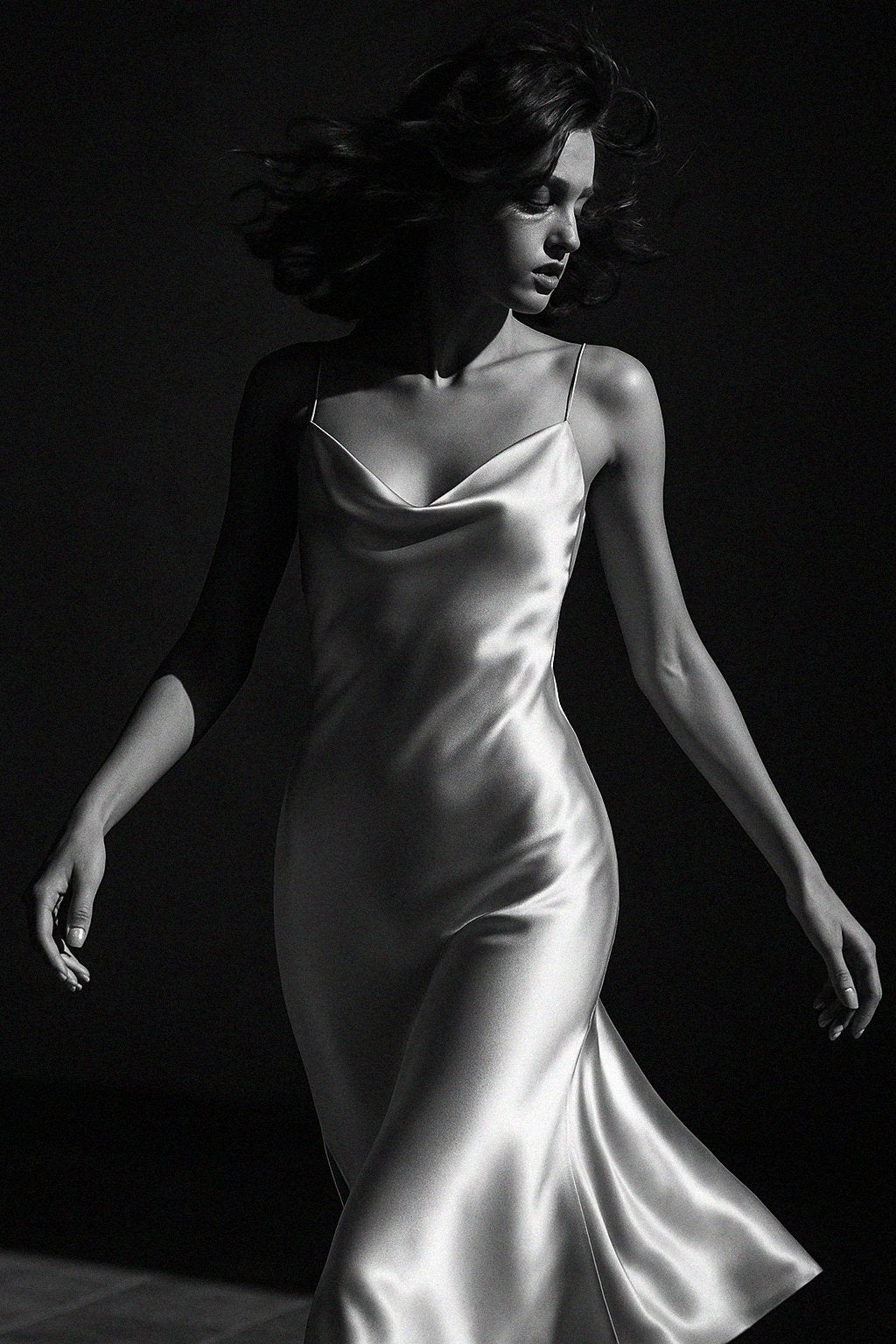 Woman in a silk slip dress against a dark background